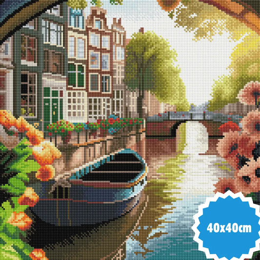 Diamond painting van Amsterdamse gracht met kleurrijke gevels, brug, blauwe boot en bloemen in bloei langs het water, formaat 40x40 cm.