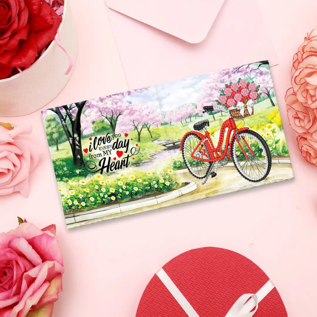 Diamond painting wenskaart met de tekst 'I love you every day from my heart' en een rode fiets met bloemenmand in een park.