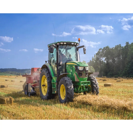 Diamond painting van een groene tractor die werkt op een goudgeel weiland onder een blauwe hemel.