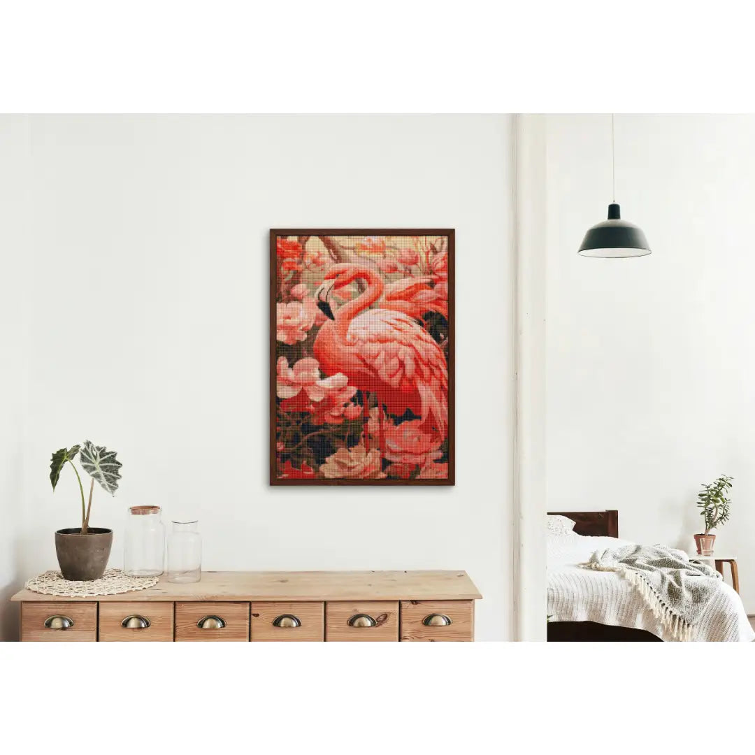 Diamond painting van een roze flamingo tussen bloemen, aan de muur boven een houten dressoir met decoratieve items.