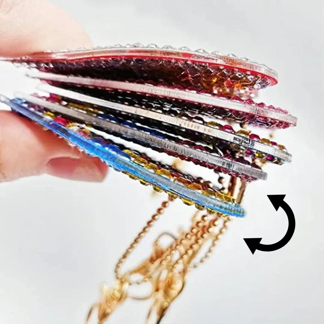 Hand die meerdere kleurrijke diamond painting sleutelhangers met glinsterende steentjes vasthoudt.