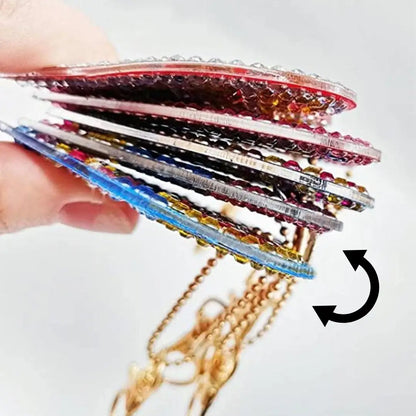 Hand die meerdere kleurrijke diamond painting sleutelhangers met glinsterende steentjes vasthoudt.